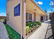 Thumbnail 4 of 27 - Leasing office entrance with signage and garden at ELEVATE Apartments HOMES, Placentia, 92870