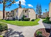 Thumbnail 5 of 27 - Apartment community pathway with green lawn at ELEVATE Apartments HOMES, Placentia, California