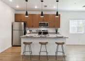 Thumbnail 12 of 25 - a kitchen with a island and three bar stools in front of a kitchen counter at Gibson Oaks, Lakeland, 33809
