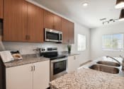 Thumbnail 14 of 25 - a modern kitchen with granite counter tops and stainless steel appliances at Gibson Oaks, Lakeland, 33809