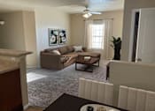 Thumbnail 2 of 18 - A living room with a brown couch and a painting on the wall.