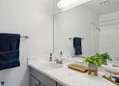Thumbnail 15 of 32 - A bathroom with a white countertop and a blue towel hanging on the wall.