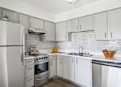 Thumbnail 1 of 32 - A modern kitchen with white cabinets and a stainless steel refrigerator.