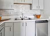 Thumbnail 3 of 32 - A modern kitchen with white cabinets and a stainless steel dishwasher.