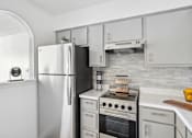 Thumbnail 2 of 32 - A white refrigerator stands next to a stove in a kitchen.