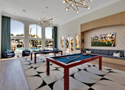 Thumbnail 43 of 57 - a billiards room with two pool tables and a tv in front of windows