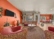Thumbnail 11 of 18 - A living room with orange walls and furniture.