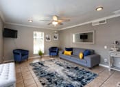 Thumbnail 23 of 28 - A living room with a grey couch, blue chairs, and a white ottoman.