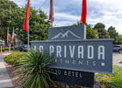 Thumbnail 13 of 28 - A sign for Privada Artments stands in front of a tree.
