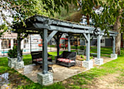 Thumbnail 19 of 28 - A gazebo with two red and white striped chairs sits in a grassy area.