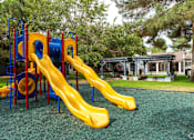 Thumbnail 17 of 28 - A playground with a yellow slide and a blue and red structure.