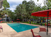 Thumbnail 16 of 28 - A pool area with red chairs and umbrellas.