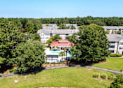 Thumbnail 44 of 50 - A large building with a red roof is surrounded by trees.
