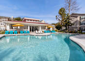Thumbnail 16 of 50 - A swimming pool with blue chairs and a yellow umbrella.