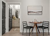 Thumbnail 31 of 43 - A dining room with a table set for two and a painting on the wall.