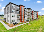 Thumbnail 8 of 43 - A row of modern apartment buildings with a grassy area in front.
