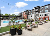 Thumbnail 3 of 43 - A pool area with chairs and plants in front of apartment buildings.