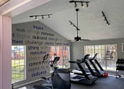 Thumbnail 31 of 32 - A gym with a wall of motivational words and exercise equipment.