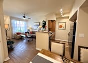 Thumbnail 2 of 20 - A living room with a kitchen area in the background.