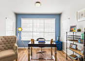 Thumbnail 19 of 57 - a living room with a blue wall and a window and a desk with a chair