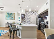Thumbnail 8 of 57 - an open kitchen and dining area with bar stools in front of a kitchen island
