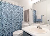 Thumbnail 12 of 28 - A bathroom with a white sink and a blue shower curtain.