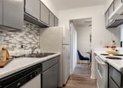 Thumbnail 2 of 28 - A kitchen with a black and white tile backsplash and a blue chair.