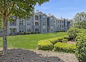 Thumbnail 3 of 15 - A large building with a green lawn in front.