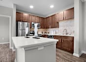 Thumbnail 5 of 15 - A kitchen with a white island and brown cabinets.