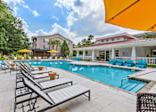 Thumbnail 19 of 50 - A pool area with sun loungers and a building in the background.