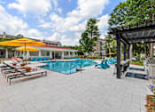 Thumbnail 18 of 50 - A pool with a yellow umbrella and blue chairs.