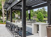 Thumbnail 26 of 50 - A barbecue grill is under a black pergola.