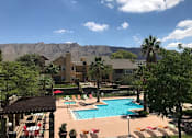 Thumbnail 24 of 32 - A pool surrounded by chairs and mountains in the background.