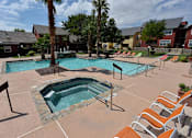 Thumbnail 22 of 32 - A pool area with a hot tub and lounge chairs.