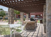 Thumbnail 25 of 32 - A patio with a table and chairs under a wooden pergola.