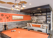 Thumbnail 11 of 31 - A pool table is in the middle of the club room with a couch and a shelf.