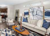Thumbnail 24 of 31 - A living room with a couch, a coffee table, and a large painting on the wall.