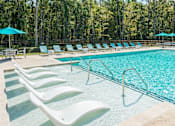 Thumbnail 18 of 31 - A pool with white lounge chairs and blue umbrellas.