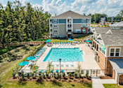 Thumbnail 2 of 31 - A large swimming pool surrounded by a fence and trees.