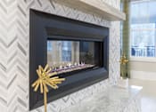 Thumbnail 27 of 31 - A black fireplace with a gold star decoration in front of it.