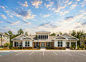 Thumbnail 4 of 31 - A large white building with a black roof and a parking lot in front.