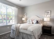 Thumbnail 7 of 41 - A bedroom with a large bed and a window with blinds.