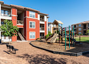 Thumbnail 23 of 41 - A playground area in front of a red apartment building.