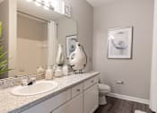 Thumbnail 9 of 41 - A bathroom with a white sink and a white toilet.