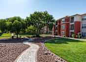 Thumbnail 37 of 41 - A residential area with apartment buildings and a gravel path.