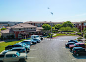 Thumbnail 40 of 41 - A parking lot with cars and a bird flying in the sky.