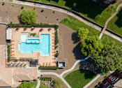 Thumbnail 39 of 41 - An aerial view of a pool surrounded by trees and a grassy area.