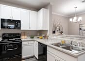 Thumbnail 1 of 41 - A kitchen with black appliances and white cabinets.