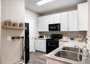 Thumbnail 2 of 41 - A kitchen with black appliances and white cabinets.