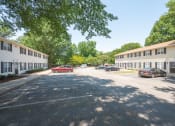 Thumbnail 8 of 13 - a parking lot with cars in front of several apartment buildings